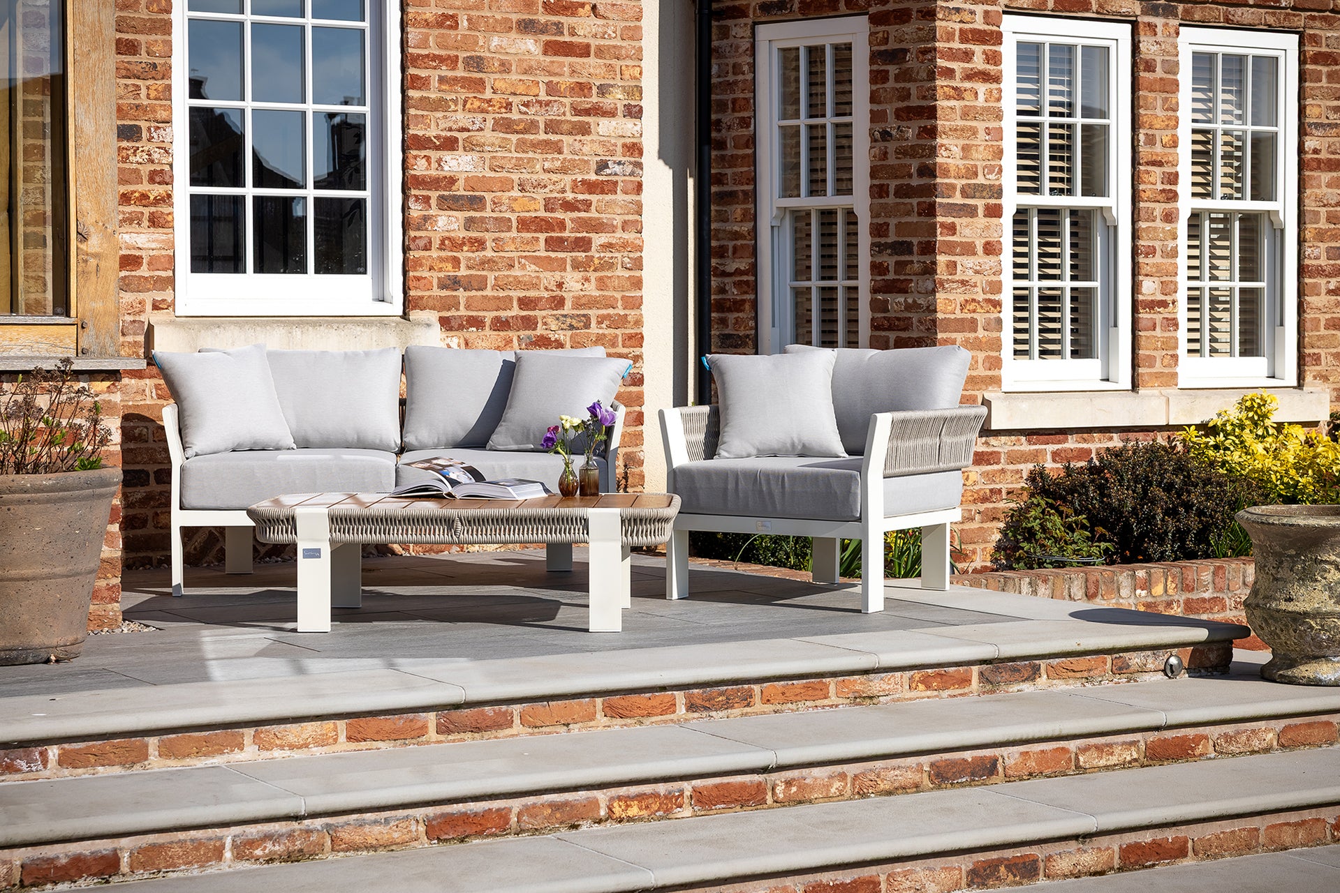 A Seatherny Rope Weave 2 Seat Sofa Set with a rectangular coffee table on a brick patio, with a white and gray color scheme.