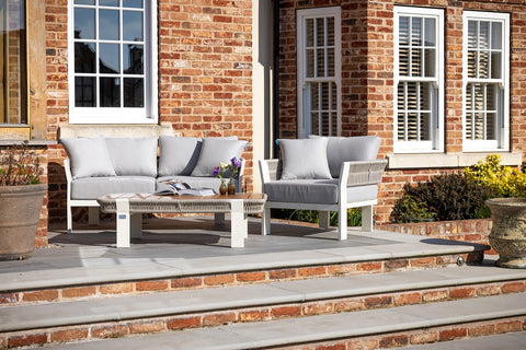 A Seatherny Rope Weave 2 Seat Sofa Set with a rectangular coffee table on a brick patio, with a white and gray color scheme.